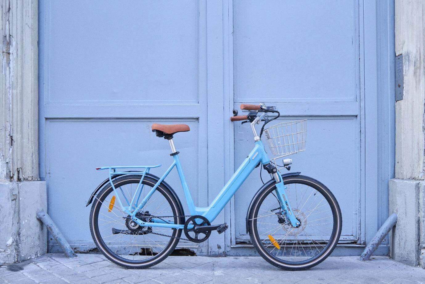 Un vélo électrique de ville devant une porte bleue