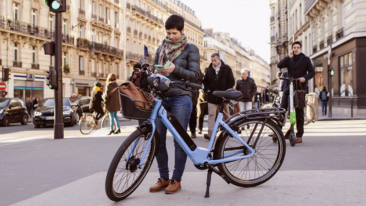 Une personne avec son vélo au milieu d'une rue