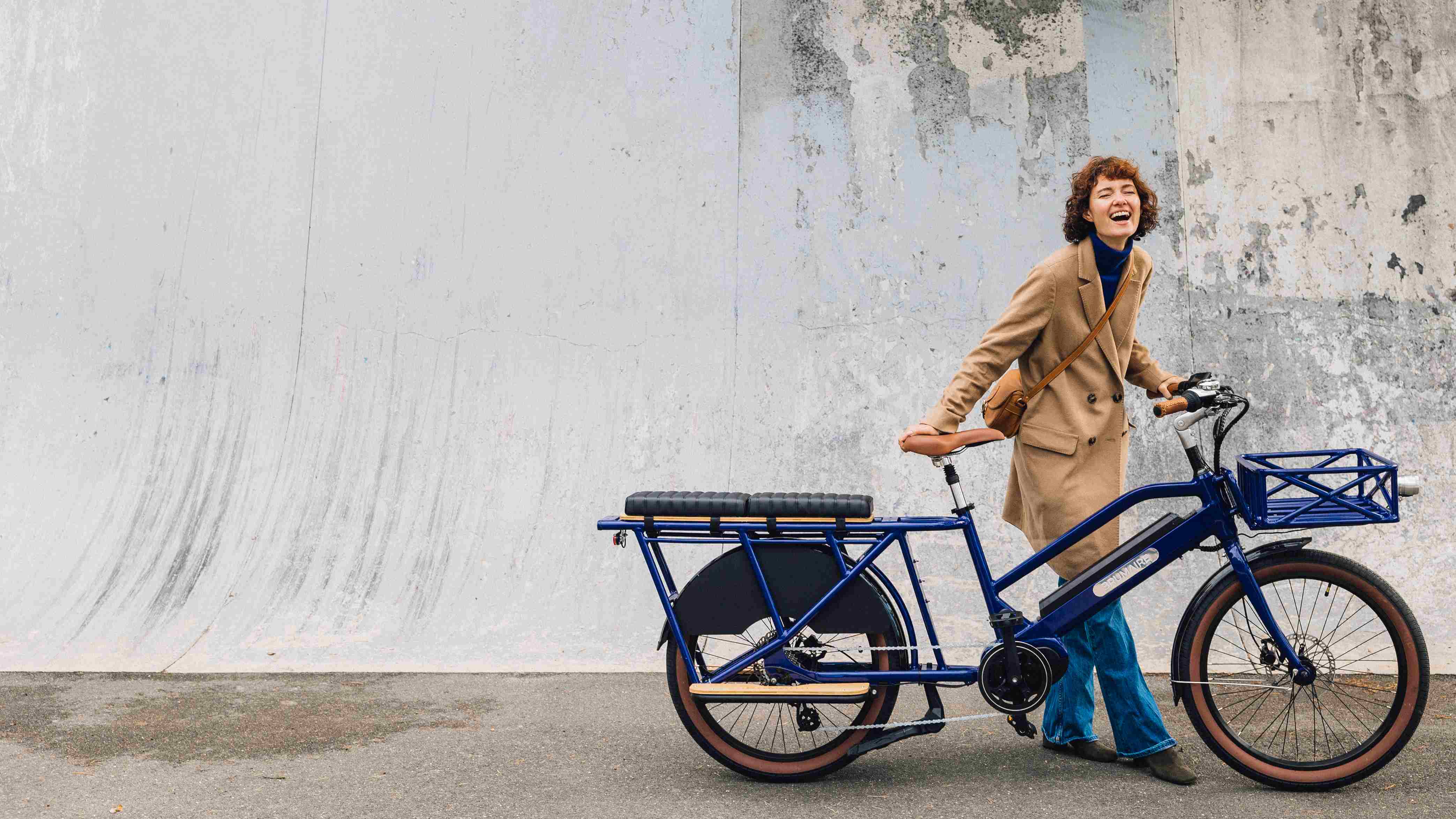 Une femme qui tient son vélo cargo bleu