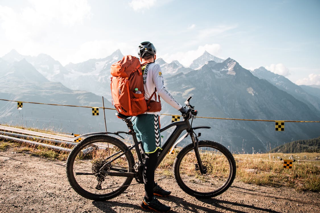 Un homme en vélo au bord d'une falaise face à une montagne