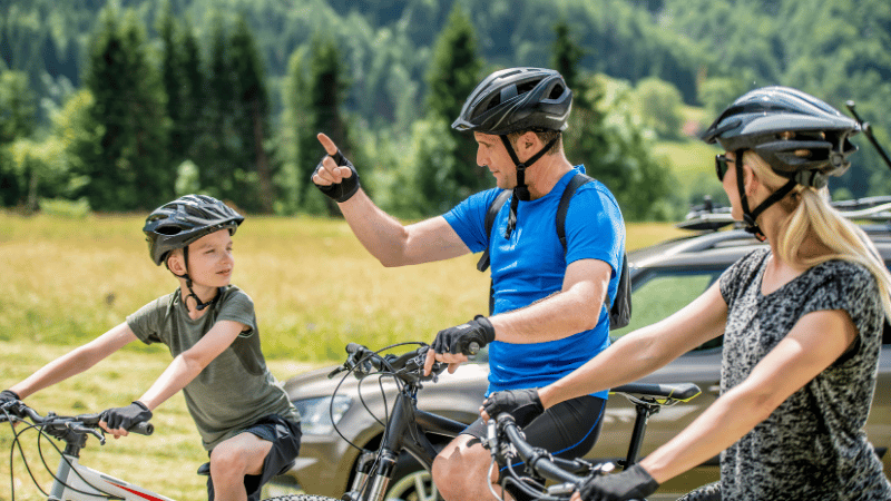 famille qui fait du vélo dans les montagnes et le père qui donne des instructions