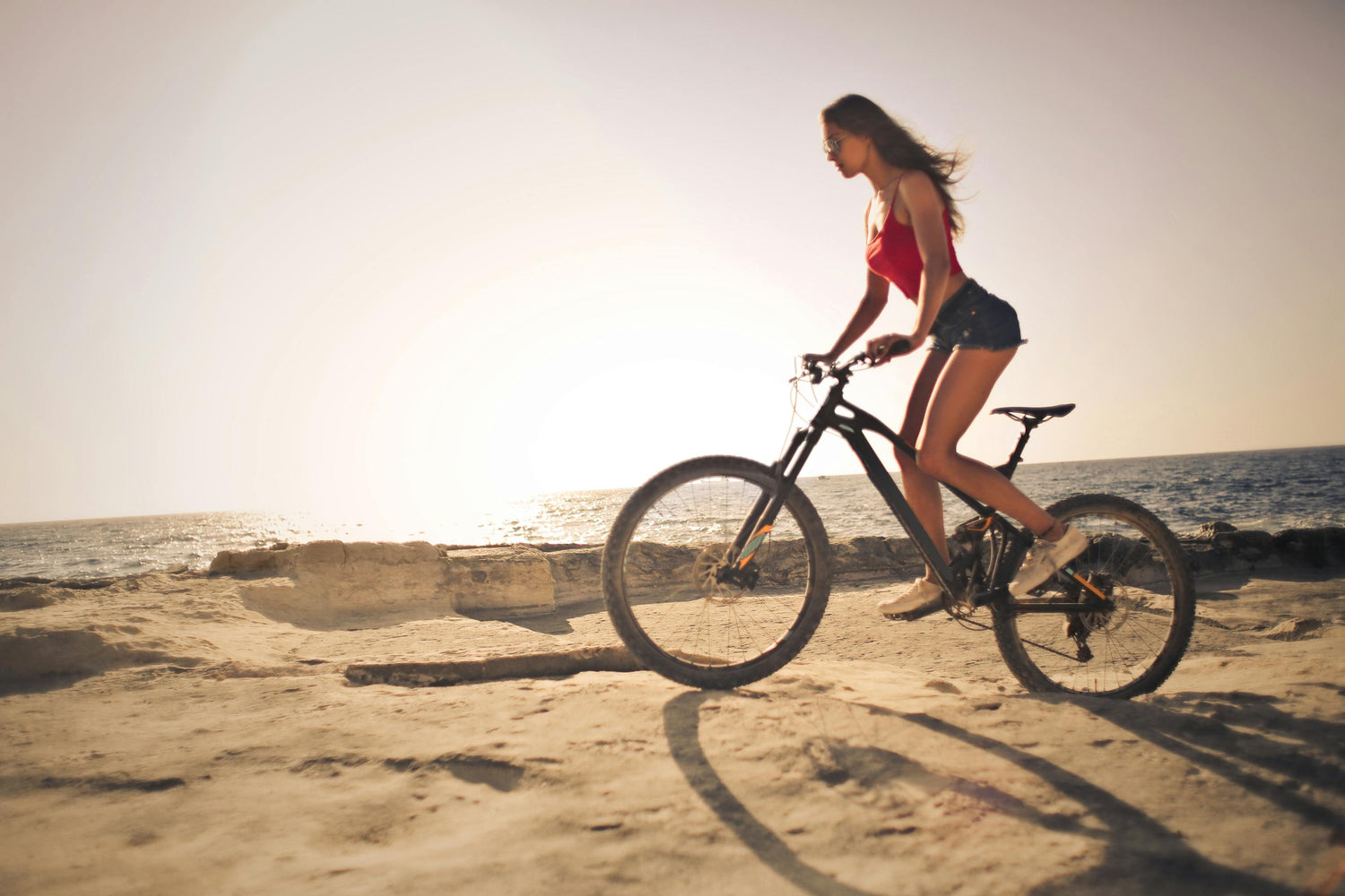 Une femme avec un vélo électrique proche d'une plage